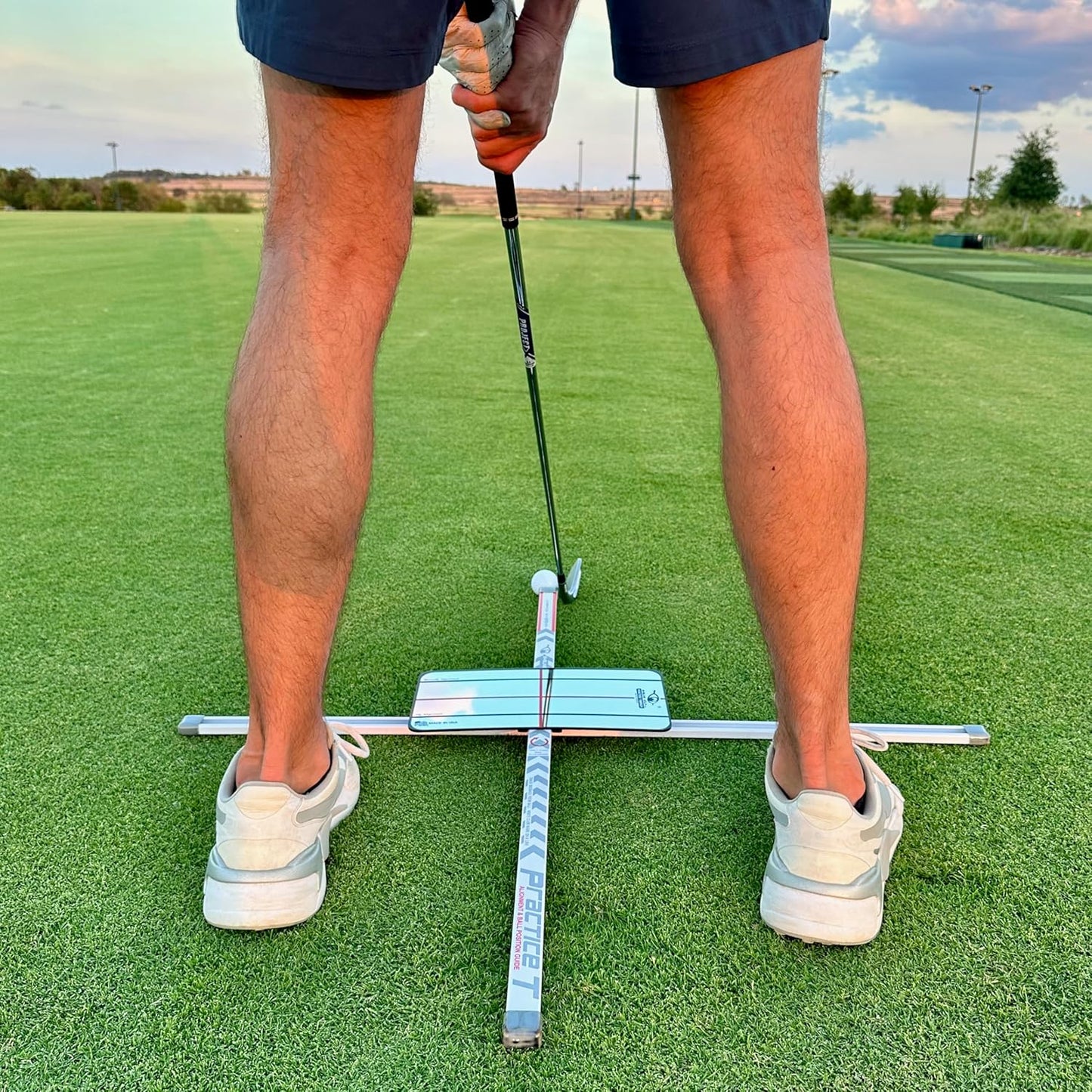 Person practicing golf with T Alignment training aid on practice range. 